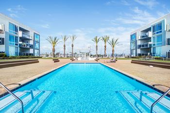 A swimming pool with apartments and palm trees in the background